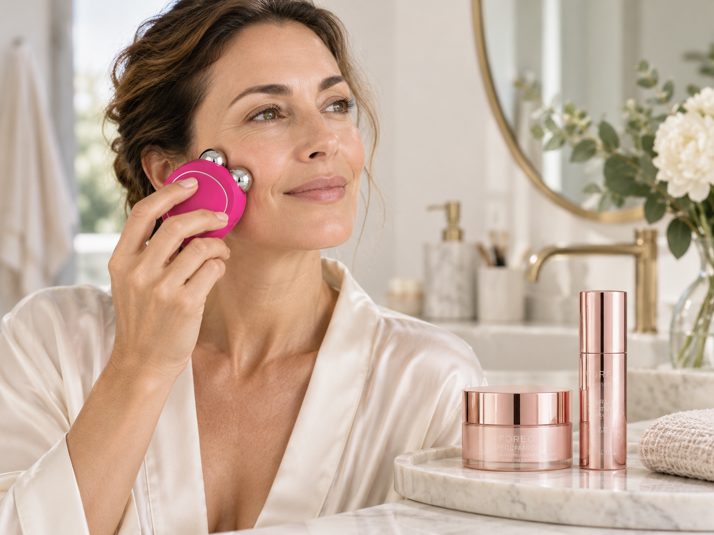 FOREO BEAR 2 Mikrostromgerät in Pink mit passendem Serum und Feuchtigkeitspflege auf hellem, cleanem Hintergrund.